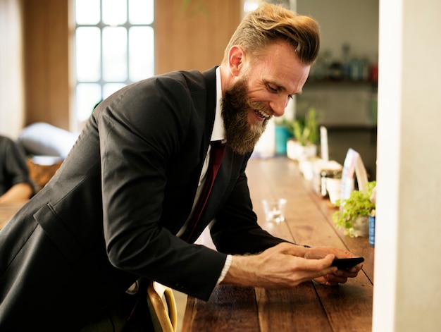 Foto gratuita uomo che si raffredda alla caffetteria con il telefono cellulare