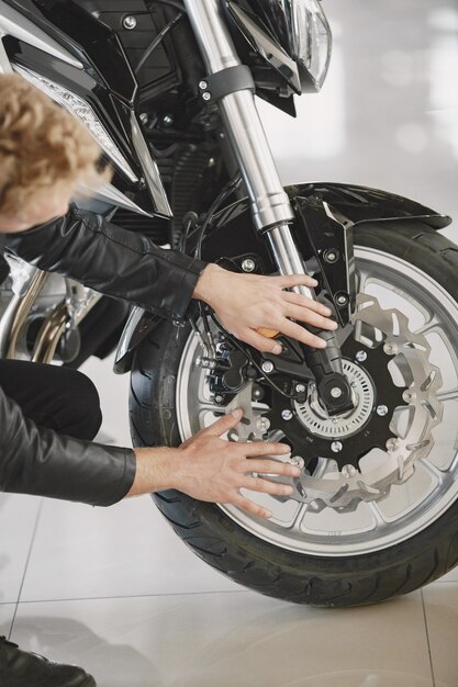 Man choosed motorcycles in moto shop. Guy in a black jacket.