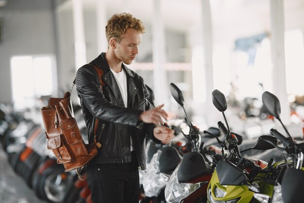 男はモトショップでバイクを選びました。黒のジャケットを着た男。