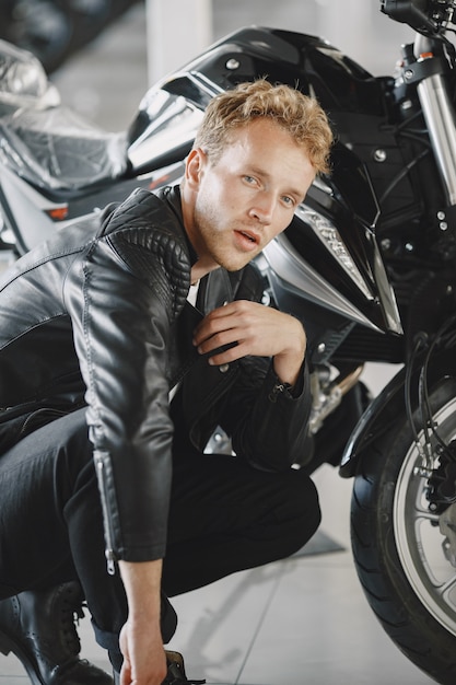 Мужчина выбирал мотоциклы в мото-магазине. Парень в черной куртке.
