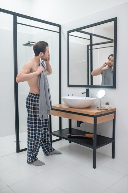 A man choosing clothing and holding a grey shirt in hands