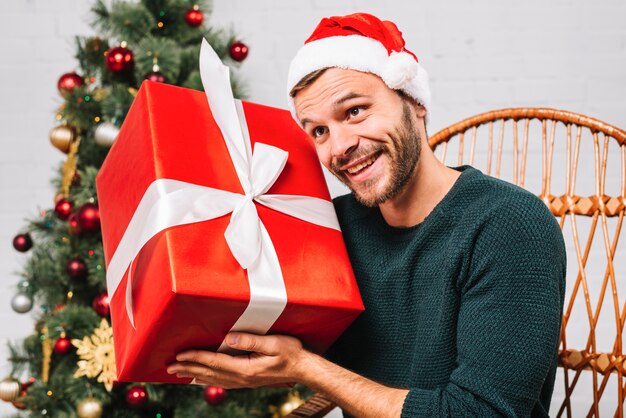 Man in Christmas hat holding present box