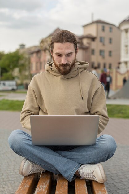 Man in the city sitting on bench and working on laptop