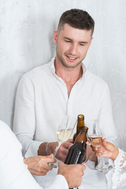 Man clanging bottle of beer with friends 