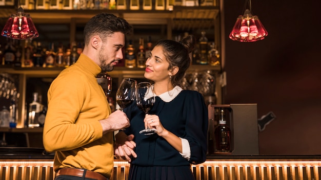 Free photo man clanging glasses of wine with smiling woman