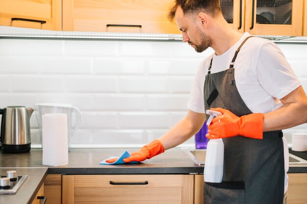 Man cleaning cabinet with rag