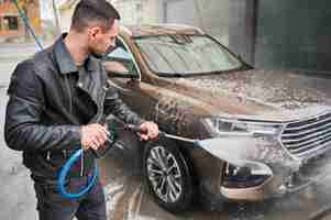 Free photo man cleaning car by water from high pressure water gun