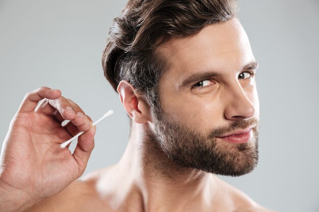 Man cleaning his ears with ear stick