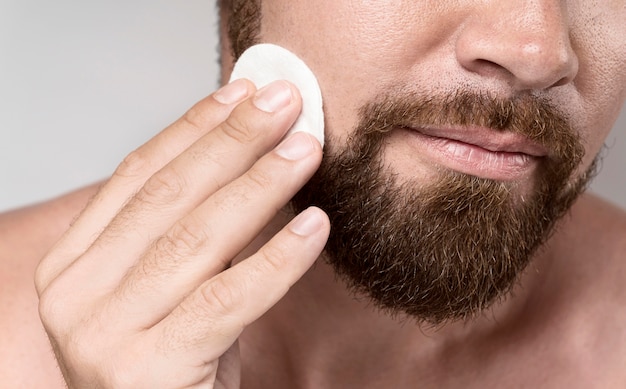 Man cleaning his face with a cleansing disk