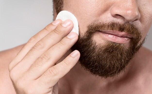 Man cleaning his face with a cleansing disk