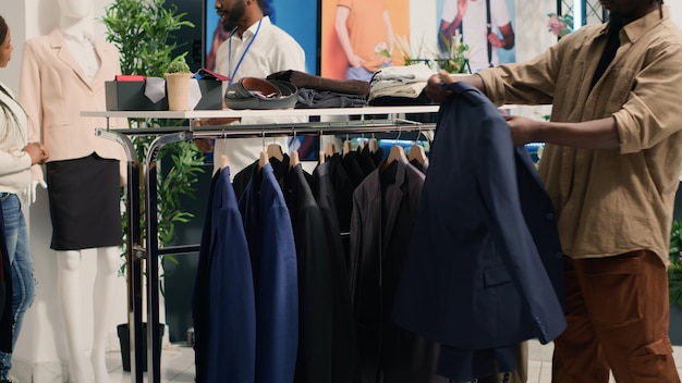 Free photo man closely looking at blazers in mall