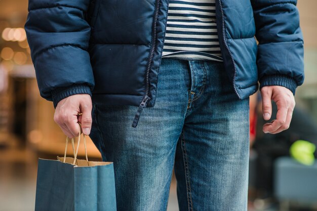 Man in coat standing holding bag