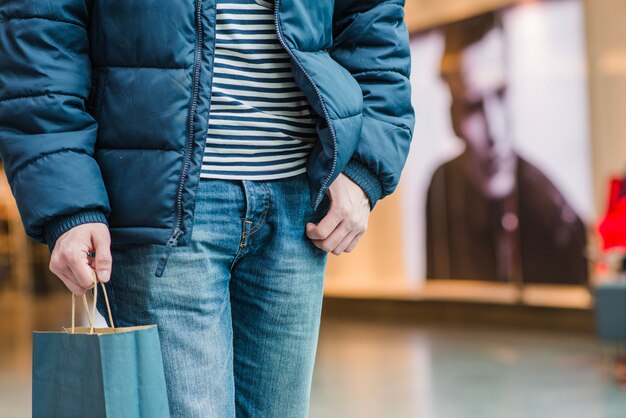 Man in coat standing holding bag