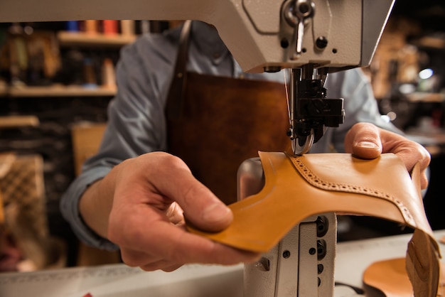 Man cobbler stitching leather parts