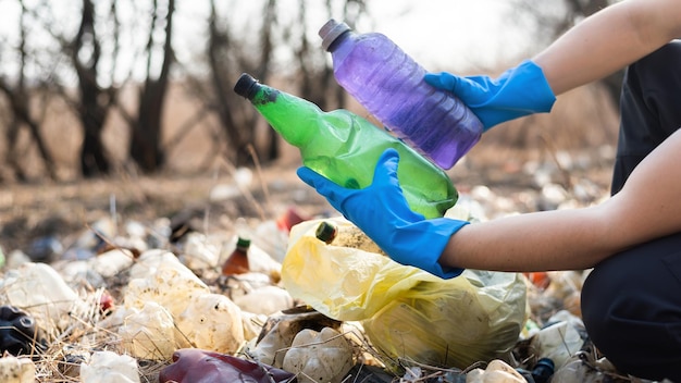 Бесплатное фото Мужчина собирает с земли разбросанные пластиковые бутылки