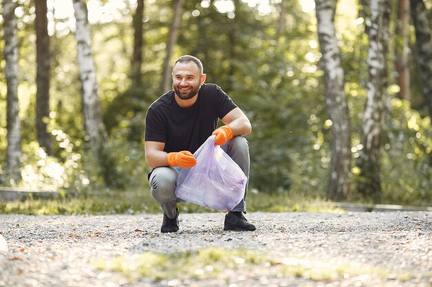 Man collects garbage in garbage bags in park