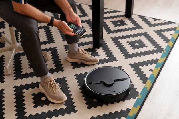 Free photo man controlling a robot vacuum with his phone