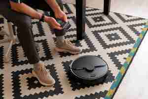 Free photo man controlling a robot vacuum with his phone