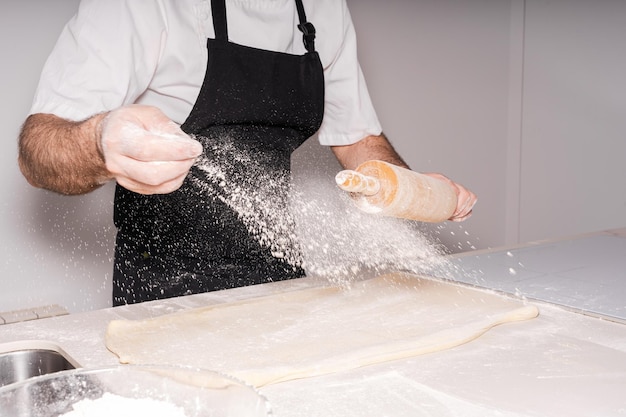 自家製クロワッサンを調理してパイ生地を準備し、小麦粉を加える男