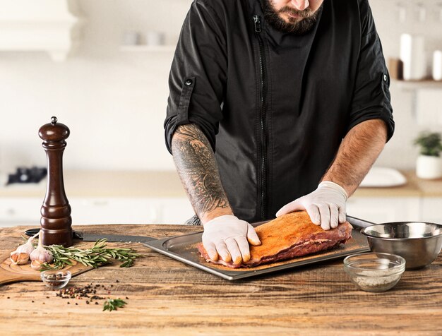 キッチンで肉ステーキを調理する男