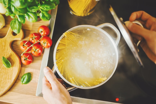 Foto gratuita uomo che cucina la pasta in acqua bollente