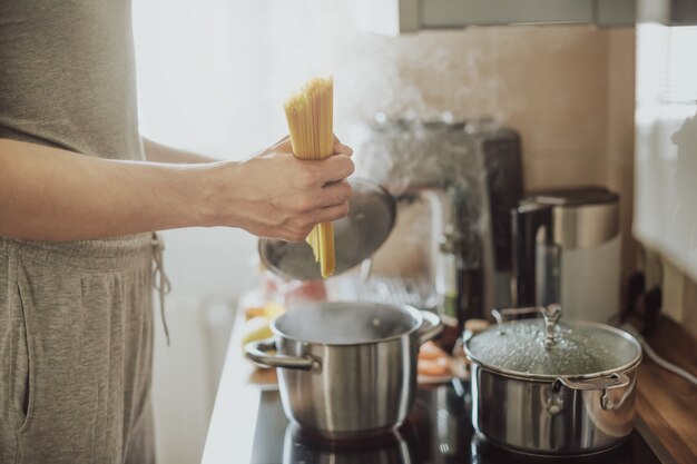 Укомплектуйте личным составом варить спагетти макаронных изделий дома на кухне. Домашняя кухня или итальянская концепция приготовления пищи.