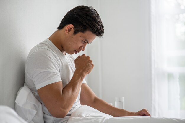 The man coughed and put his hand over his mouth and sat down on the bed.