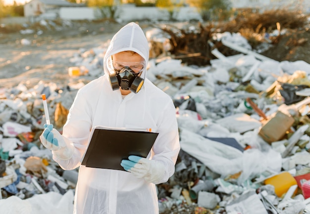 ゴミ箱のつなぎ服を着た男。調査する。生態学、環境汚染の概念。