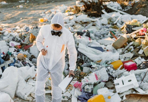 Man in coveralls at trash pill, doing research