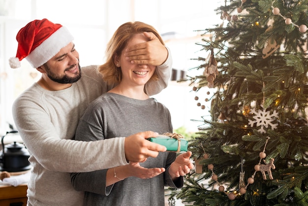 クリスマスプレゼントのために彼の妻の目を覆っている男