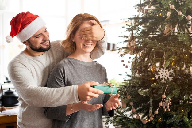 Man covering his wife's eyes for a christmas present