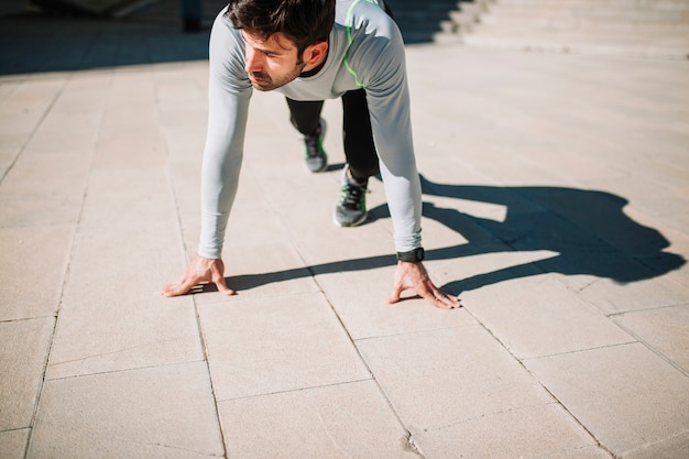 Man in crouch start pose on pavement