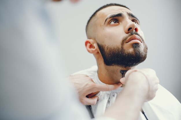 The man cuts his beard in the barbershop