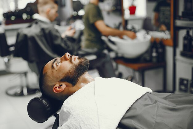Человек режет бороду в парикмахерской.