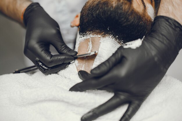 The man cuts his beard in the barbershop