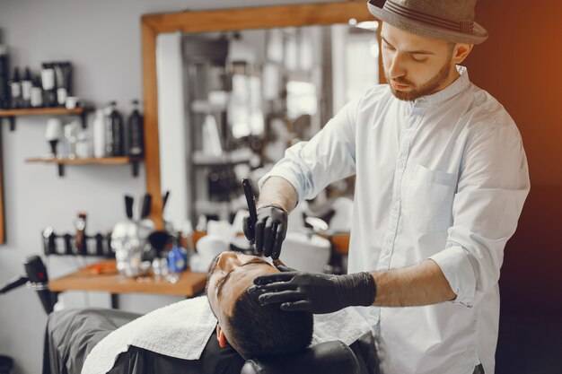 The man cuts his beard in the barbershop