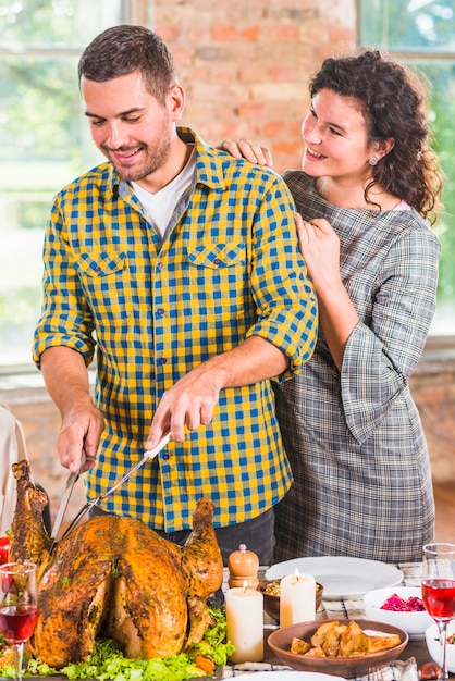 Equipaggi il taglio del pollo al forno alla tavola vicino alla donna