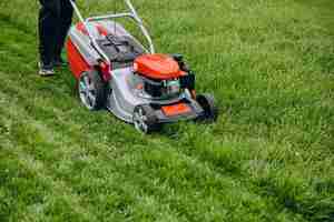 Free photo man cutting grass with lawn mover in the back yard