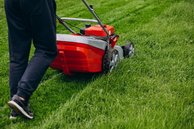 Человек косит траву газонным двигателем на заднем дворе