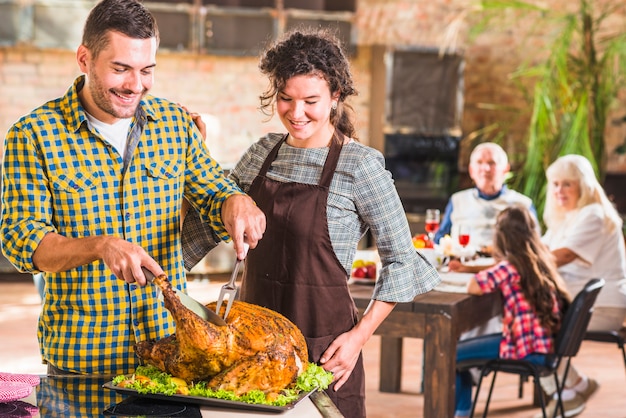 Man cutting roasted ham near woman 