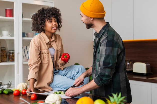 Man cutting vegetables and looking at his girlfriend