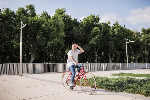 Man cyclist shielding his eye while riding bike