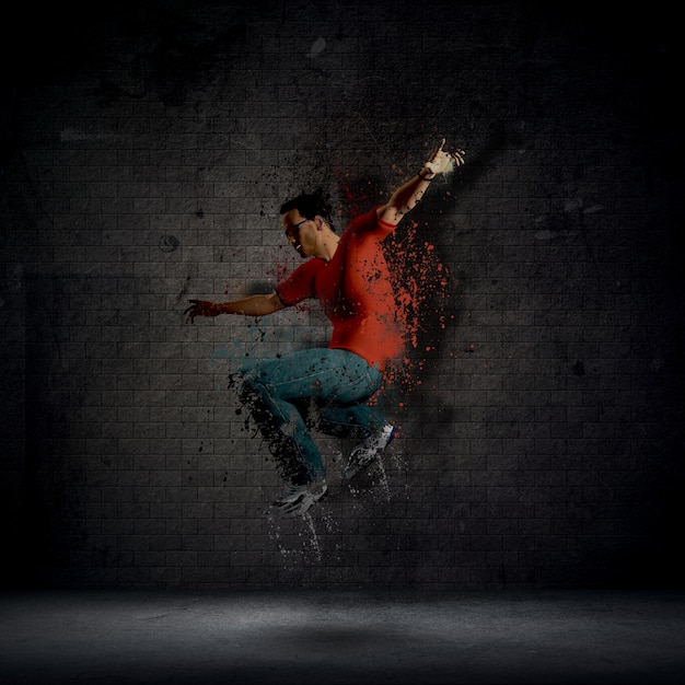 Free photo man dancing against a dark brick wall