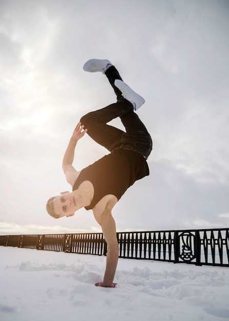 雪の中で片手に立っている間ヒップホップに踊る男