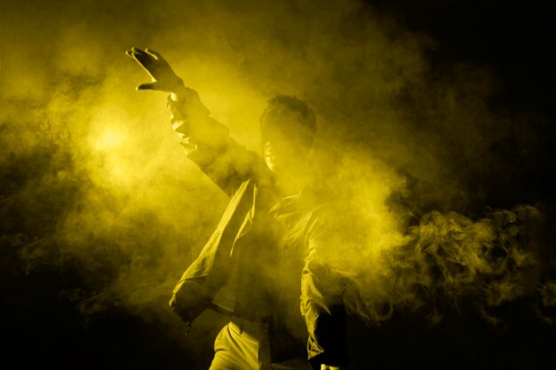 照明の光で煙の中で踊る男