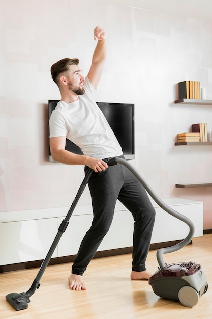 Man dancing with vacuum cleaner long shot