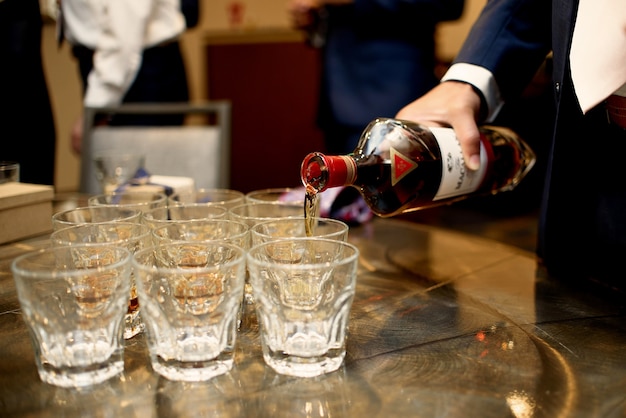 Man in dark blue suit pours whisky in the glasses