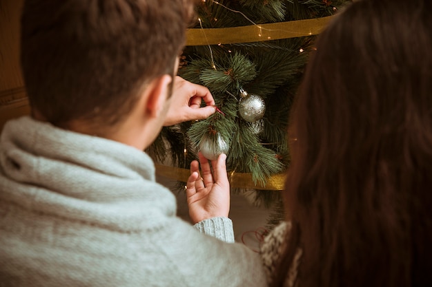 ボールでクリスマスツリーを飾る男