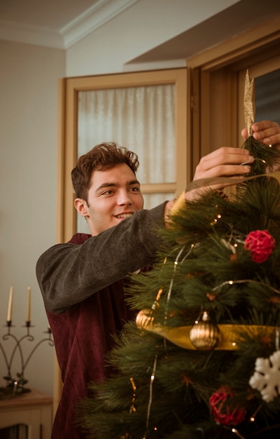 Man decorating Christmas tree with star