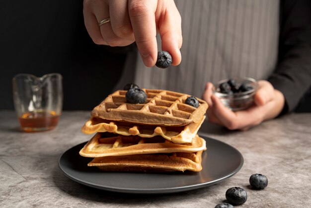 Man decorating stack of waffles with blueberries
